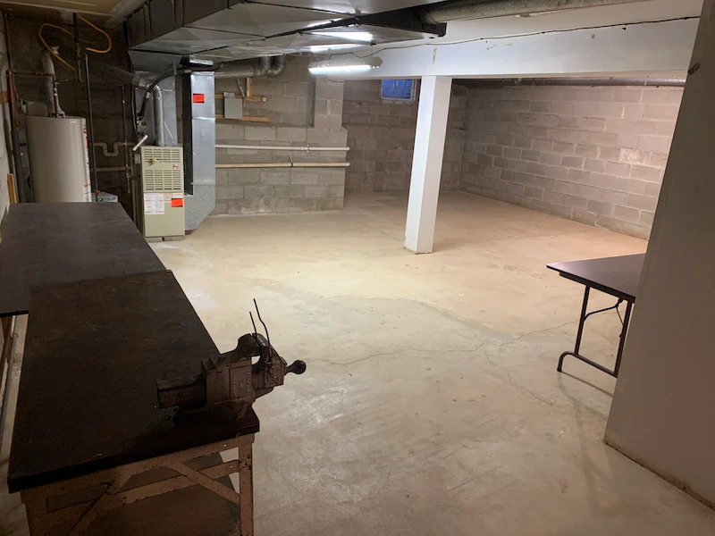 A Cranford, North Jersey basement completely cleared of all boxes and debris, showing a clean concrete floor and organized workshop area after professional junk removal.