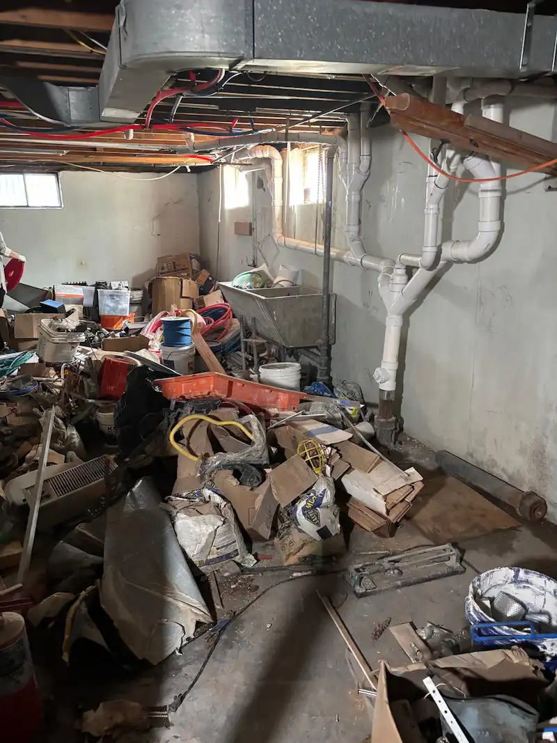 A cluttered North Jersey basement filled with renovation debris, cardboard boxes, and household junk before being cleared by JunkDoctors.