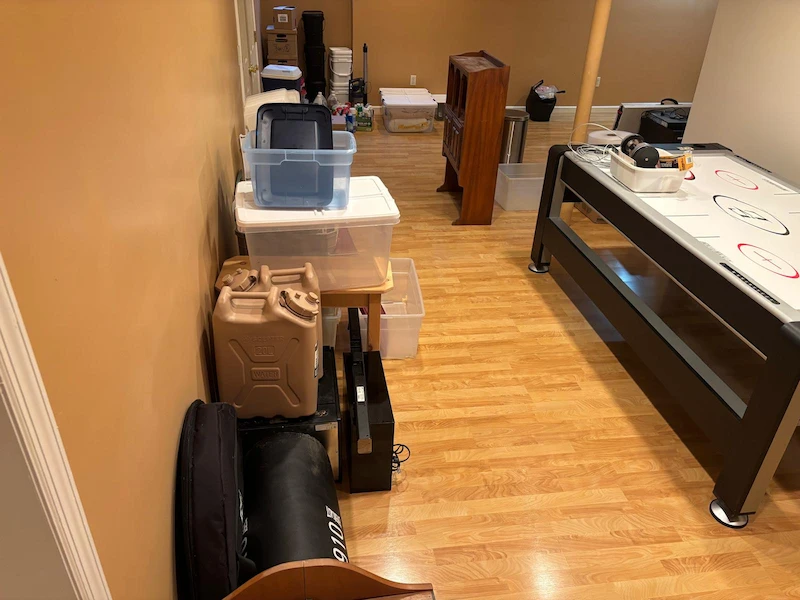A finished Randolph, North Jersey basement with storage bins, old furniture, and household items before a JunkDoctors cleanout.