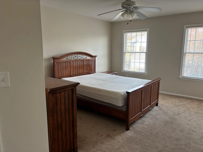 A heavy wood bed frame, mattress, and dresser in a Summit, New Jersey bedroom before being removed by JunkDoctors.