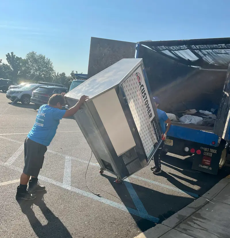 Professional disposal of a large commercial refrigerator unit being loaded into a Junkdoctors hauling truck.