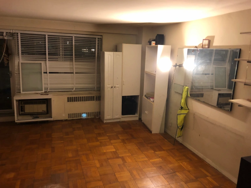 The Jersey City, New Jersey apartment after a professional hoarder cleanout, showing a fully cleared room with the floor and walls visible.