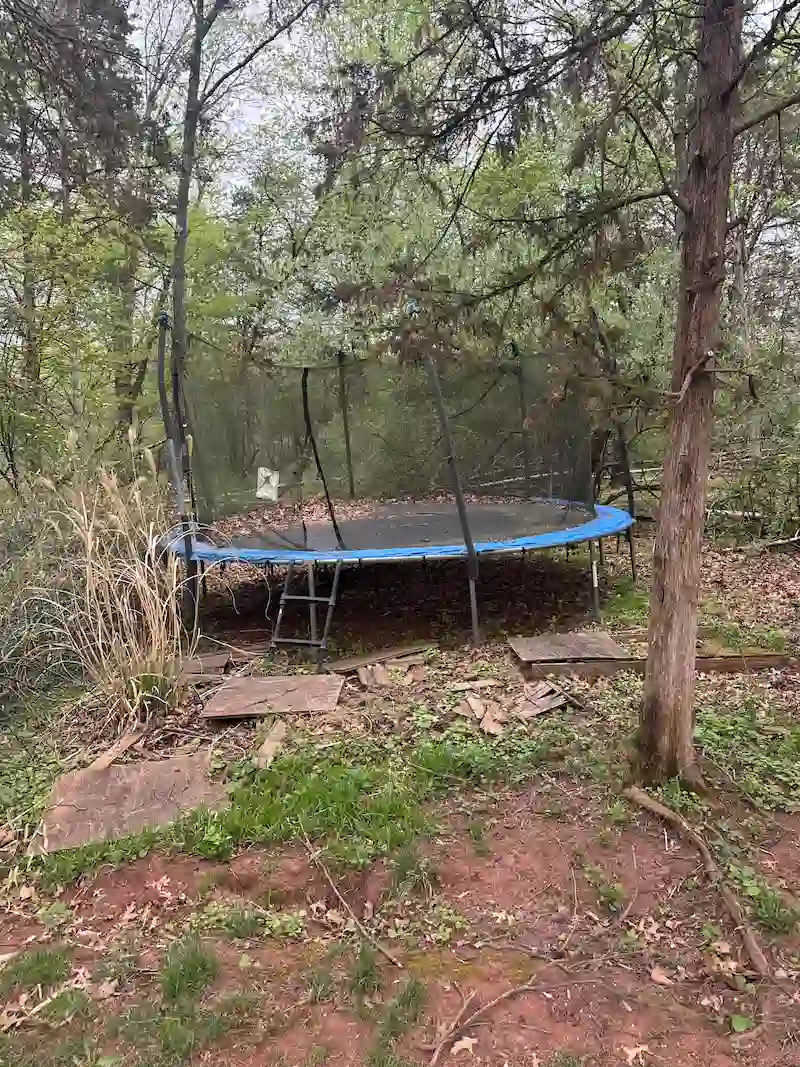 An old, damaged backyard trampoline and debris before being removed by JunkDoctors in North Jersey.