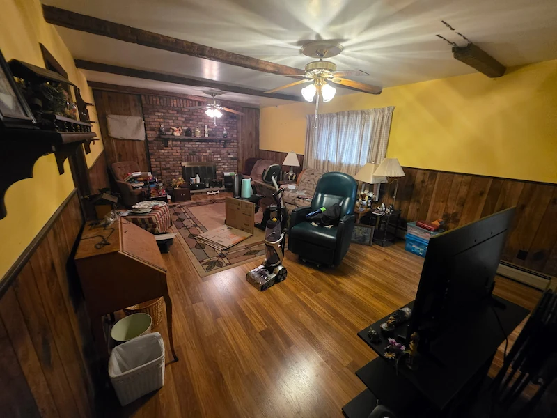 A cluttered Hackensack, North Jersey living room featuring old furniture and an elliptical machine before a JunkDoctors cleanout.