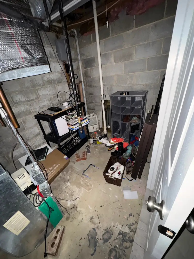 A cluttered utility room in a North Jersey basement filled with old shoes, boxes, and miscellaneous junk before being cleared by Junk Doctors.